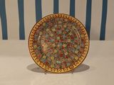 a colorful plate on a stand on a table