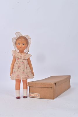 une petite poupée qui se tient à côté d'une boîte