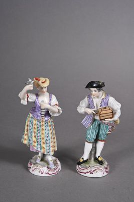trois figurines en porcelaine représentant des personnages tenant des instruments de musique, posées sur un fond gris