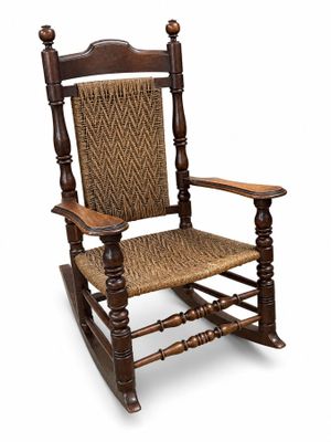 un vieux fauteuil à bascule en bois avec une assise tressée sur fond blanc