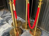 two golden stanches with red ropes on the floor