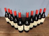 six bottles of red wine lined up on a wooden table