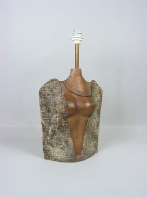 sculpture représentant un torse féminin posé sur un rocher, surmonté d'une lampe