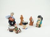 five figurines of people that are sitting on a white surface
