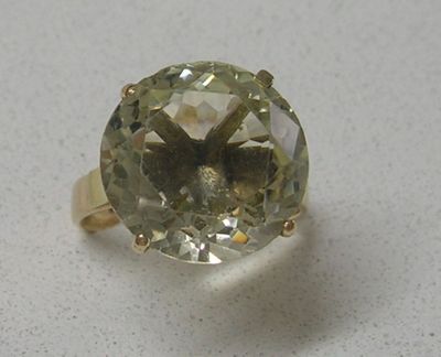 une image représentant une bague ornée d'une pierre verte sur un fond blanc