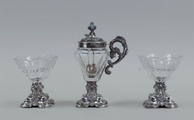 three pieces of silver and glass on a white surface