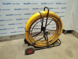 a yellow hose on a cart in front of a wall