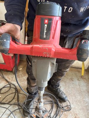 un homme qui utilise une perceuse électrique sur le sol