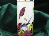 a white vase with a bird and flowers on it