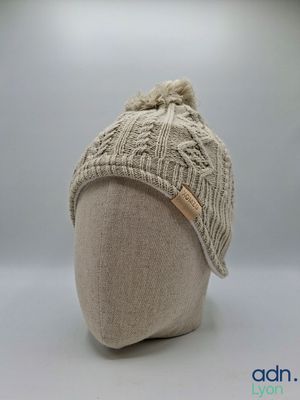 the hat is knitted and has a pom pom on top of it