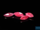 a group of three pink gems sitting on top of a black surface