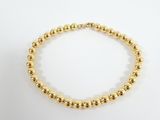 a gold beaded bracelet on a white background
