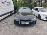 une BMW noire garée sur un parking à côté d'une camionnette blanche