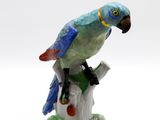 une figurine représentant un perroquet perché sur une branche d'arbre