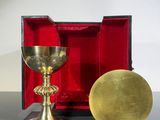 un calice en or et une boîte rouge posés sur une table