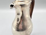 a silver coffee pot with a wooden handle on a table