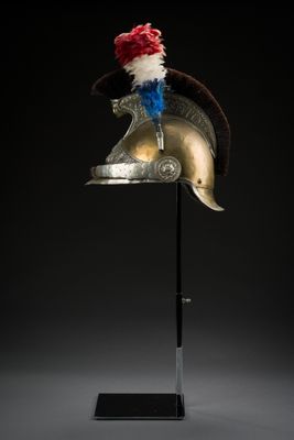 un casque posé sur un support, orné d'une plume rouge, blanche et bleue