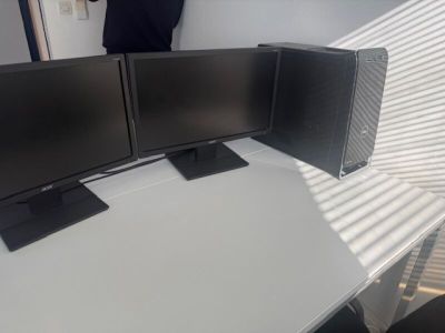 three computer monitors sitting on top of a white desk