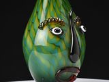 a green and black vase with a face on it