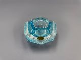 un petit objet en verre bleu posé sur une surface blanche