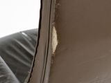 a close up of a brown leather chair with a hole in the back