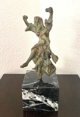 statue d'une femme posée sur un socle en marbre, elle-même posée sur une table en bois