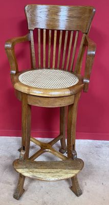 une photo d'une chaise en bois avec une assise tressée, posée sur un sol recouvert de moquette
