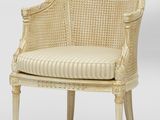 une chaise en osier blanc avec un coussin rayé et des pieds en bois