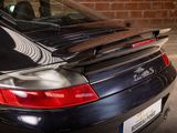 a black porsche parked in a parking lot with a skateboard on the back of the car