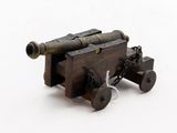 a small wooden toy cannon on wheels on a white surface