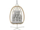 the hanging chair is made of wicker and has a cushion on it