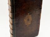 an old book with a brown cover sitting on top of a white surface