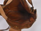 a brown purse with a strap hanging from it ' s side