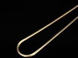a close up of a gold necklace with a chain on a black background