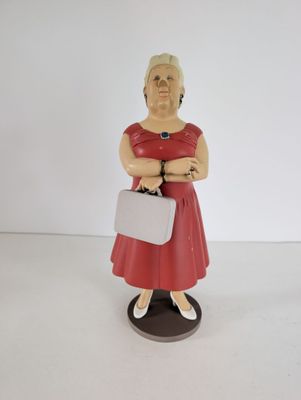 figurine représentant une femme en robe rouge avec une valise