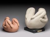 deux sculptures en céramique représentant des mains et des pieds, posées sur un socle noir