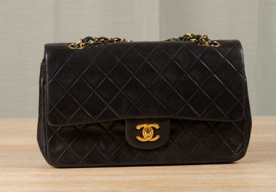 a black chanel bag sitting on top of a wooden table