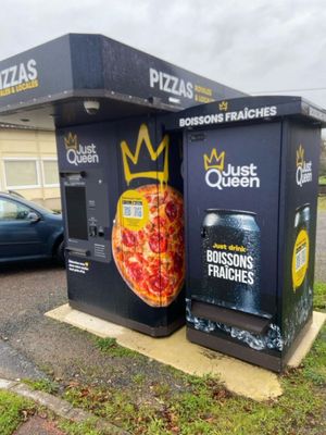 deux distributeurs automatiques sur lesquels figurent des pizzas, situés devant un immeuble