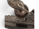 bronze statue of a bird with a ball in its beak