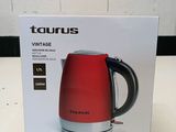 the box of a red tea kettle sitting on top of a table