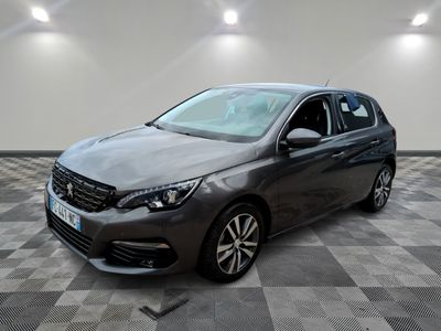 une voiture grise est garée dans une grande pièce au sol en damier