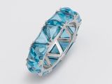 un gros plan d'une bague ornée de cristaux bleus sur fond blanc