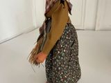 a small doll that is standing on a white surface