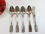 several spoons, forks, and a bowl of strawberries sit on a table