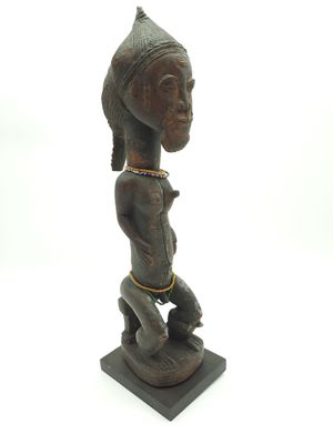statue d'une femme coiffée d'une coiffe, posée sur un socle en bois