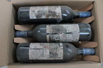 three bottles of wine are in a cardboard box on a table