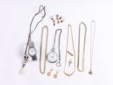 many different necklaces and watches laid out on a white surface