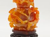 chinese carved orange jade vase on stand on white background