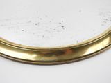 a close up of a mirror with a gold rim on a white surface
