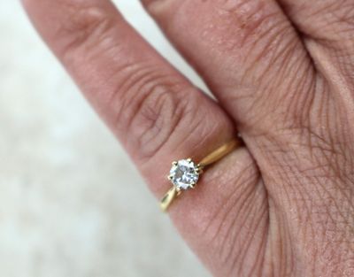 la main d'une personne tenant une bague en or sertie d'un diamant
